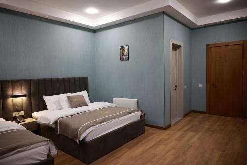 a bedroom with two beds and a blue wall at DADIANI Inn in Zugdidi