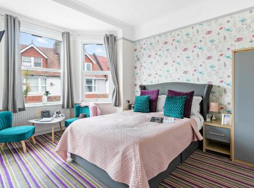 a bedroom with a bed with purple and blue pillows at Cherwood Guest House in Paignton