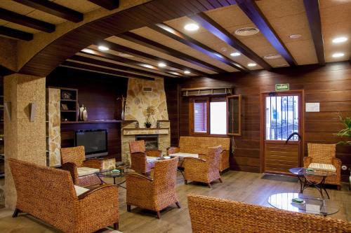 a lobby with wicker chairs and tables and a television at Hotel Comendador in Carranque