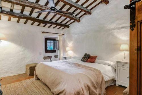 1 dormitorio con cama y pared blanca en Masia 1612 Muy cerca de las playas Costa Brava, en Calonge