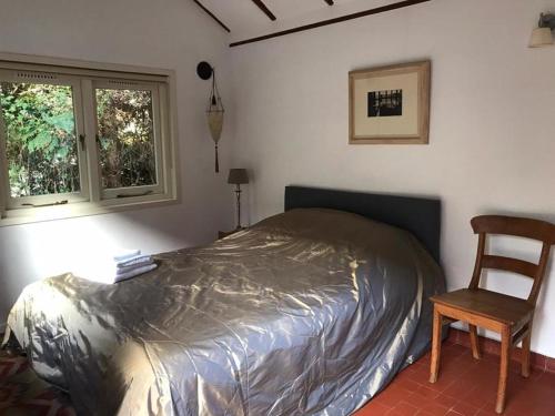 een slaapkamer met een bed, een stoel en een raam bij Duinappartementen Schoorl in Schoorl