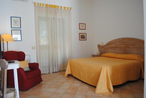 a bedroom with a bed and a red chair at Hotel Giardino Giamperduto in Bernalda