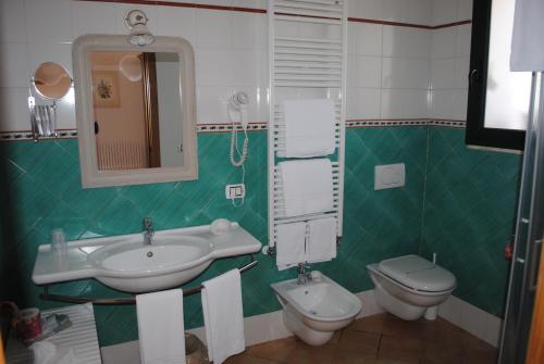 a green and white bathroom with a sink and a toilet at Hotel Giardino Giamperduto in Bernalda