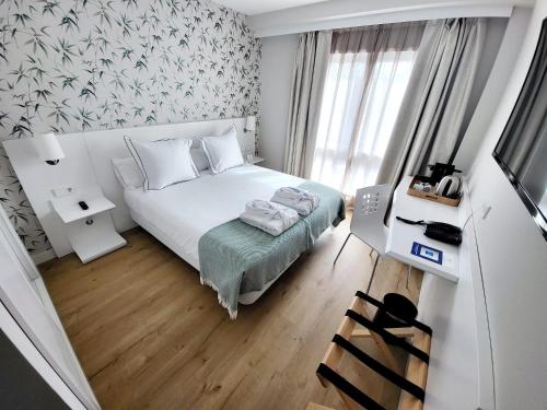 a small bedroom with a white bed and a window at Hotel Monte Rozas in Las Rozas de Madrid