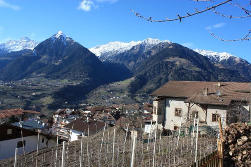 a village in the mountains with snow covered mountains at Kampflhof Apartments in Schenna
