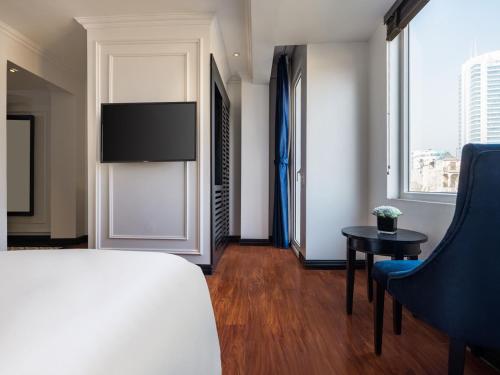 a bedroom with a bed and a chair and a table at The Flower Boutique Hotel & Travel in Hanoi