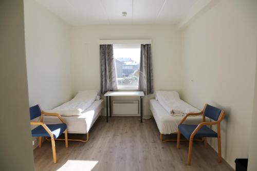 Zimmer mit 2 Betten, 2 Stühlen und einem Fenster in der Unterkunft Hostel Oslofjord in Stabekk