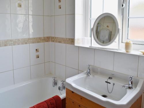 a bathroom with a tub and a sink and a mirror at Foston Grange Cottage in Bulmer