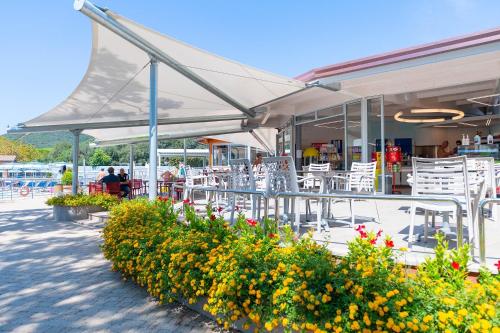 a patio with white tables and chairs and flowers at Camping Village Baia Azzurra in Castiglione della Pescaia