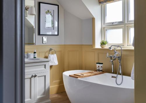 a bathroom with a large tub and a sink at The Montagu Arms in Beaulieu