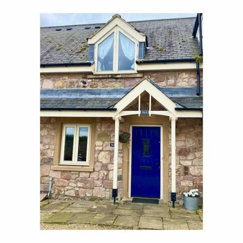 a brick house with a blue door and windows at Sailors Snug in Beadnell