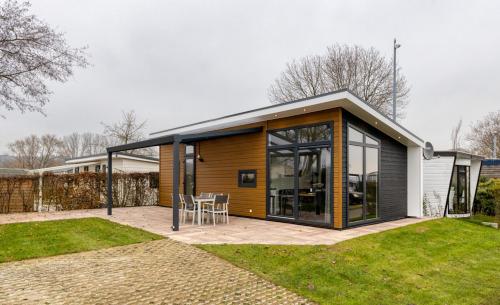 a small house with glass doors and a patio at Recreatiepark Jachthaven De Veerstal Lathum - Luxe Chalet in Lathum