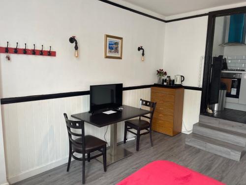 um quarto com uma mesa com cadeiras e uma televisão em Modern Studio with Free Parking near sea-station-shops em Portslade