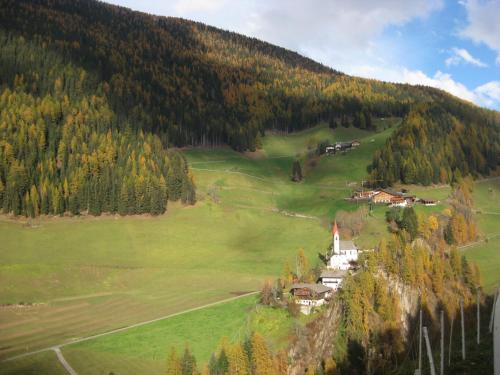 a village on a hill with a church in a field at Oberhöher Apt Talblick in San Pietro