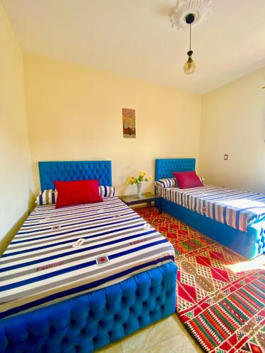 two beds in a room with blue and red at Horus pyramids view in Cairo