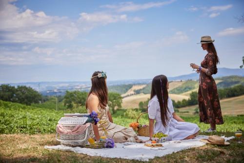 three women sitting on a picnic blanket in a field at Antica Dimora in San Gimignano