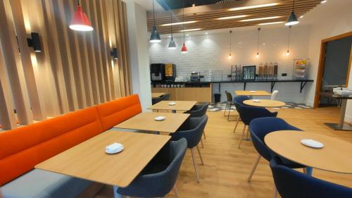 a restaurant with wooden tables and blue chairs at Holiday Inn Express Bilbao Airport by IHG in Derio