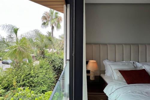 1 dormitorio con balcón con cama y ventana en Beverly Ocean Suite - By AppartAli en Casablanca