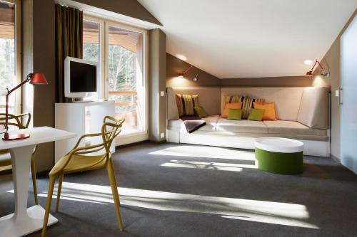 a room with a bed and a desk and a tv at Gästehaus by Stoos Hotels in Stoos