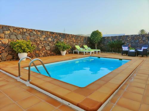 una piscina en un patio con una pared de piedra en Villa Jardín Atteneri, en La Vegueta