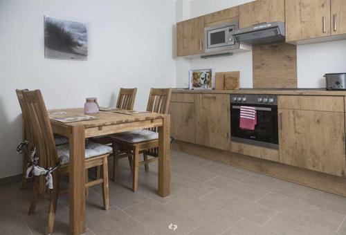 een keuken met een houten tafel met stoelen en een fornuis bij DUENENZEIT App Nr 5 max 4 Pers in Dierhagen