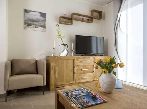 een woonkamer met een televisie, een stoel en een tafel bij DUENENZEIT App Nr 5 max 4 Pers in Dierhagen