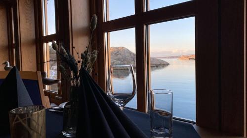 a table with two glasses and a view of the water at Sirevåg Konferansehotell AS in Sirevåg