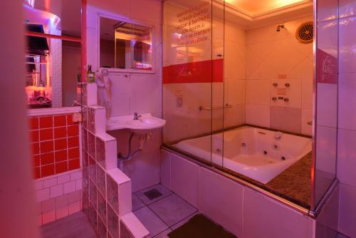 y baño con bañera y lavamanos. en Motel Kaskata en Santa Cruz do Sul