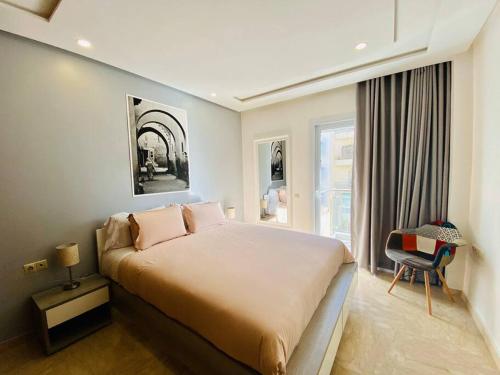 Un dormitorio con una cama y una silla y una ventana. en Cosy Triangle D Or Bourgogne - By AppartAli, en Casablanca