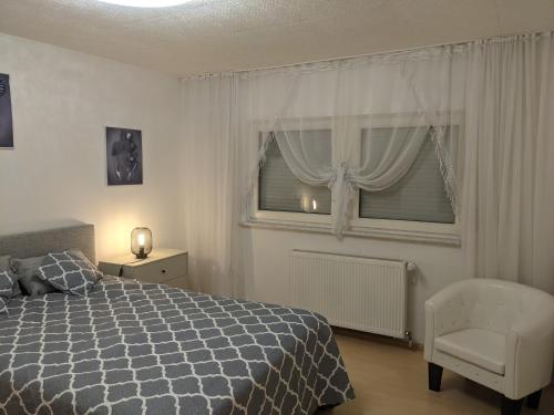 a bedroom with a bed and a chair and a window at Ferienwohnung Ela in Bexbach