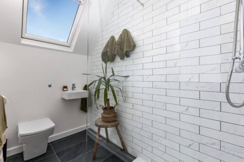 a white bathroom with a toilet and a plant at Beautifully presented holiday home near the beach in Churston Ferrers