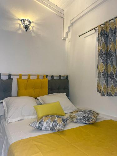 - une chambre avec un lit doté d'oreillers jaunes et blancs dans l'établissement Studio Maracuja, à Pointe-Noire