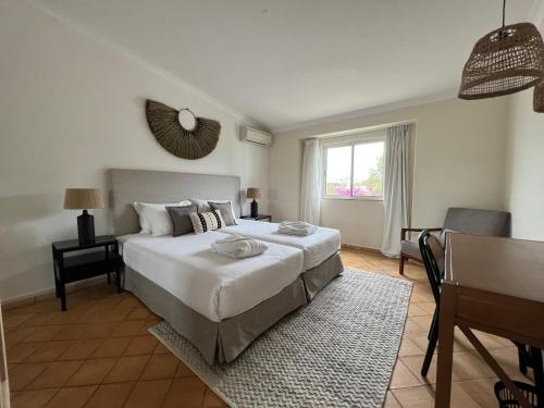 a bedroom with a large white bed and a table at Pestana Palm Gardens in Carvoeiro