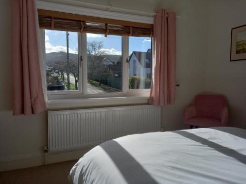 a bedroom with a bed and a window with a red chair at Grange Croft in Ben Rhydding