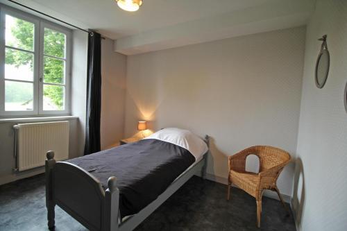 een slaapkamer met een bed, een stoel en een raam bij Les 3 tilleuls in Bellac