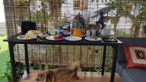 a dog laying under a table with food on it at Bloom Garden Bed & Breakfast in Siem Reap