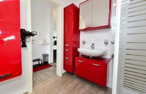La salle de bains est pourvue de placards rouges et d'un lavabo. dans l'établissement Domicilio Azzurro, à Lindau