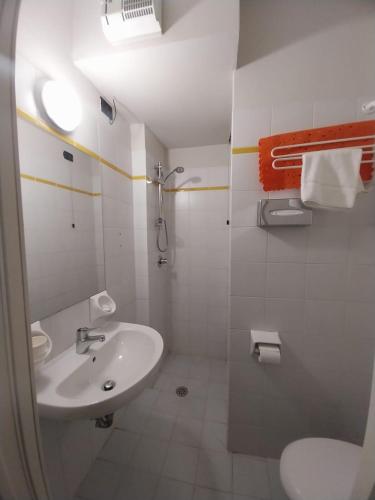 a white bathroom with a sink and a toilet at Hotel Cumilì in Capo di Ponte