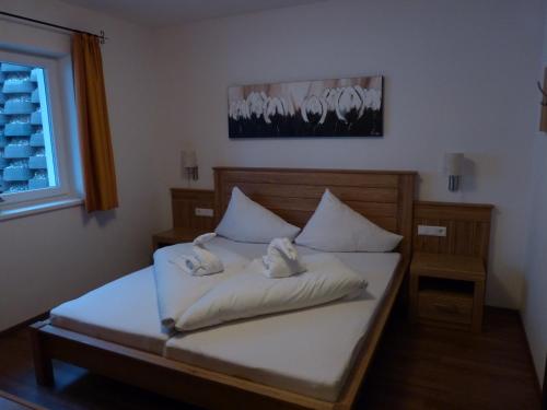 a bedroom with a bed with white sheets and a window at Apartmán Fürth in Kaprun