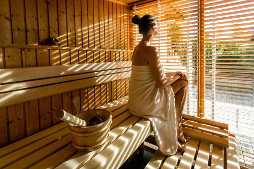 a woman sitting on a bench in a sauna at Bergesgrün in Oberstdorf