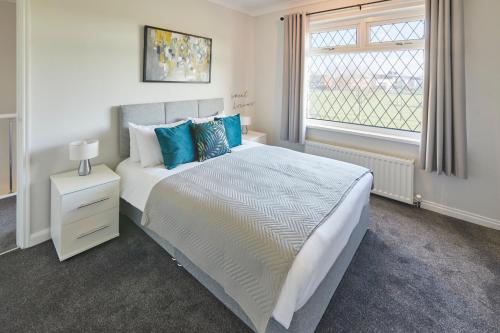 a white bedroom with a large bed with blue pillows at Host & Stay - Armitage Road in Redcar
