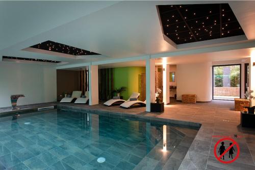 a swimming pool with two beds in a room at Europe Haguenau – Hotel & Spa in Haguenau