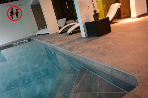 a swimming pool with a tile floor and chairs at Europe Haguenau – Hotel & Spa in Haguenau