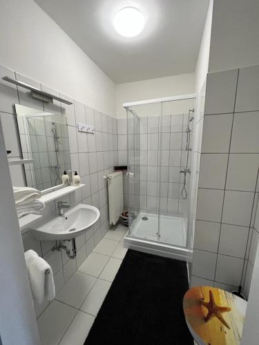 a white bathroom with a shower and a sink at Pannonia Appartements in Bad Tatzmannsdorf