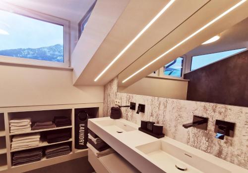 La salle de bains est pourvue d'un lavabo et d'une fenêtre. dans l'établissement Panorama Lodge Edelweiss, à Gosau