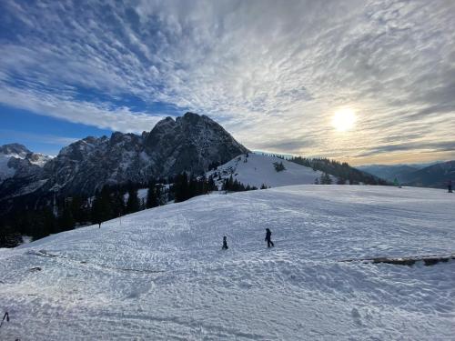 two people are skiing down a snow covered mountain at Panorama Lodge Edelweiss in Gosau