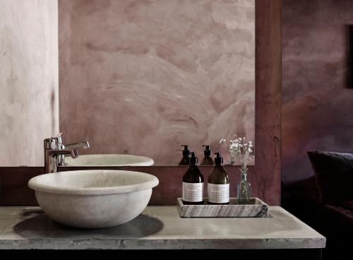 a bathroom with two sinks and two bottles of wine at The Norrmans Farmhouse Boutique Hotel in Klippinge