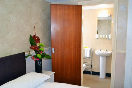 Schlafzimmer mit einer Holztür, die zu einem Waschbecken führt in der Unterkunft Lyndene Hotel in Blackpool