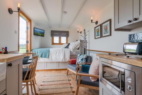 a kitchen and living room with a bed in a room at Outbak Shepherds Hut in Cheltenham