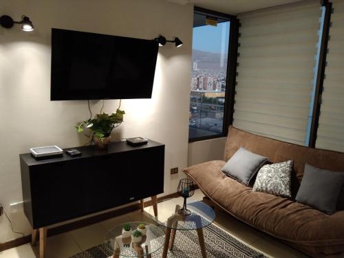 a living room with a couch and a flat screen tv at Departamento sector Cavancha in Iquique
